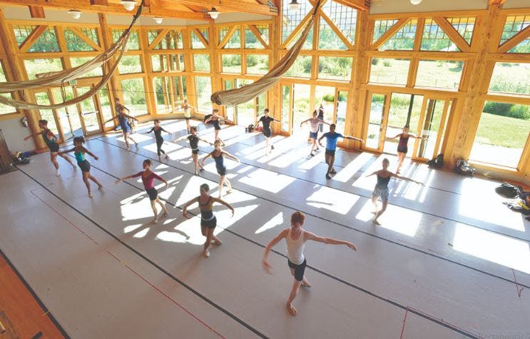 People in a large room with wooden beams practicing ballet