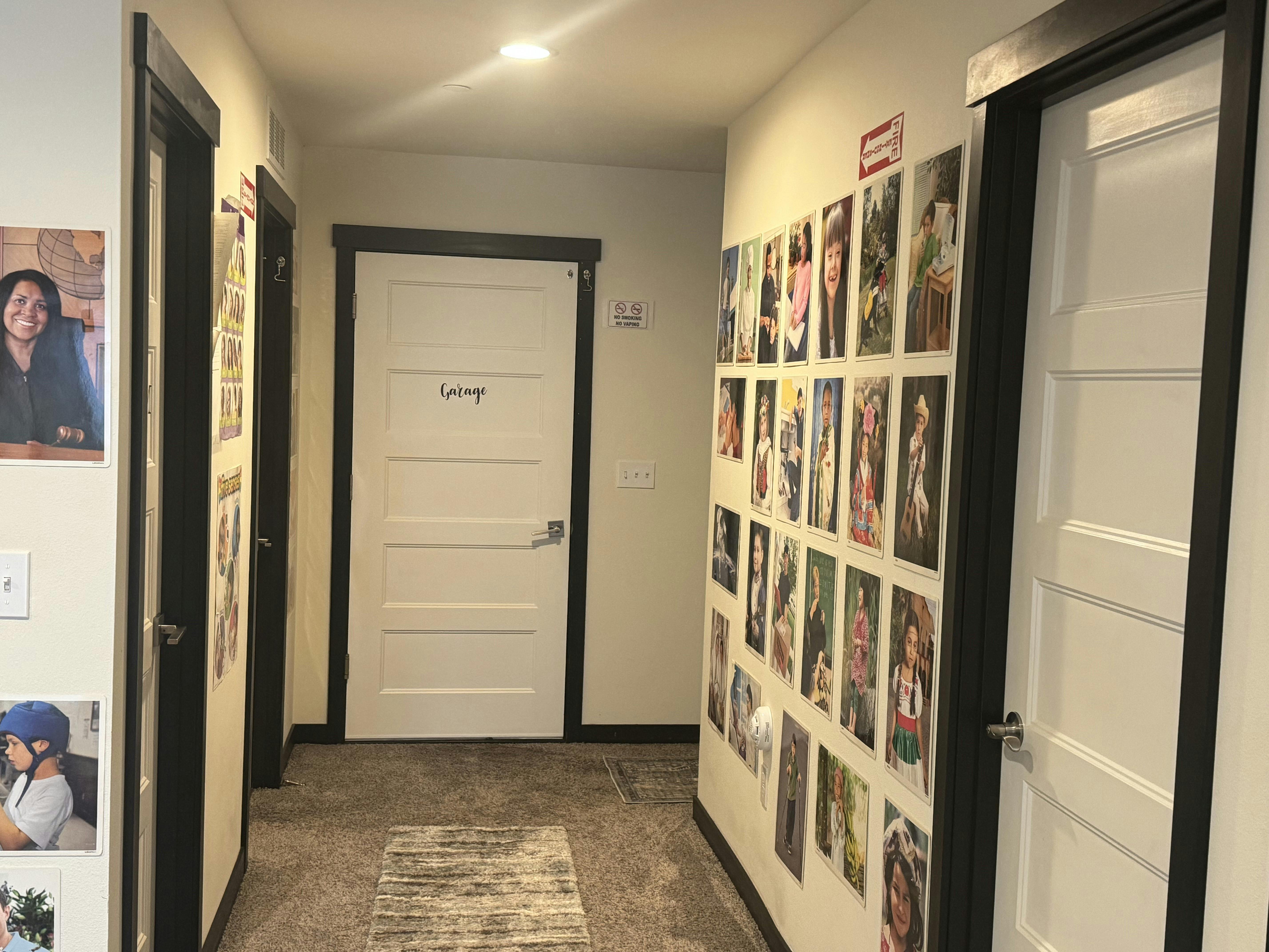 Hallway with multiple doors and photos displayed on the walls