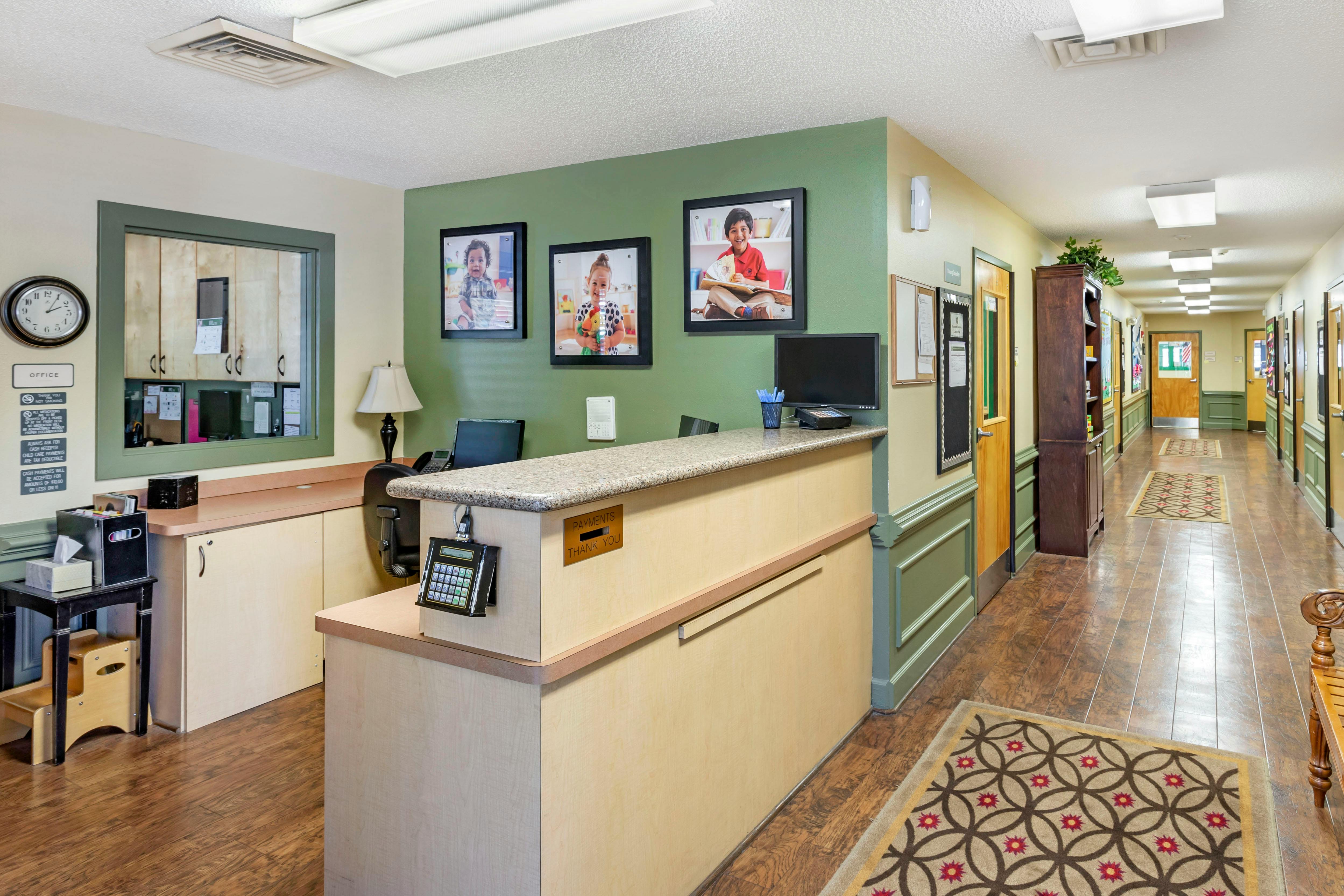 Reception desk with office sign and a long hallway lined with doors and rugs