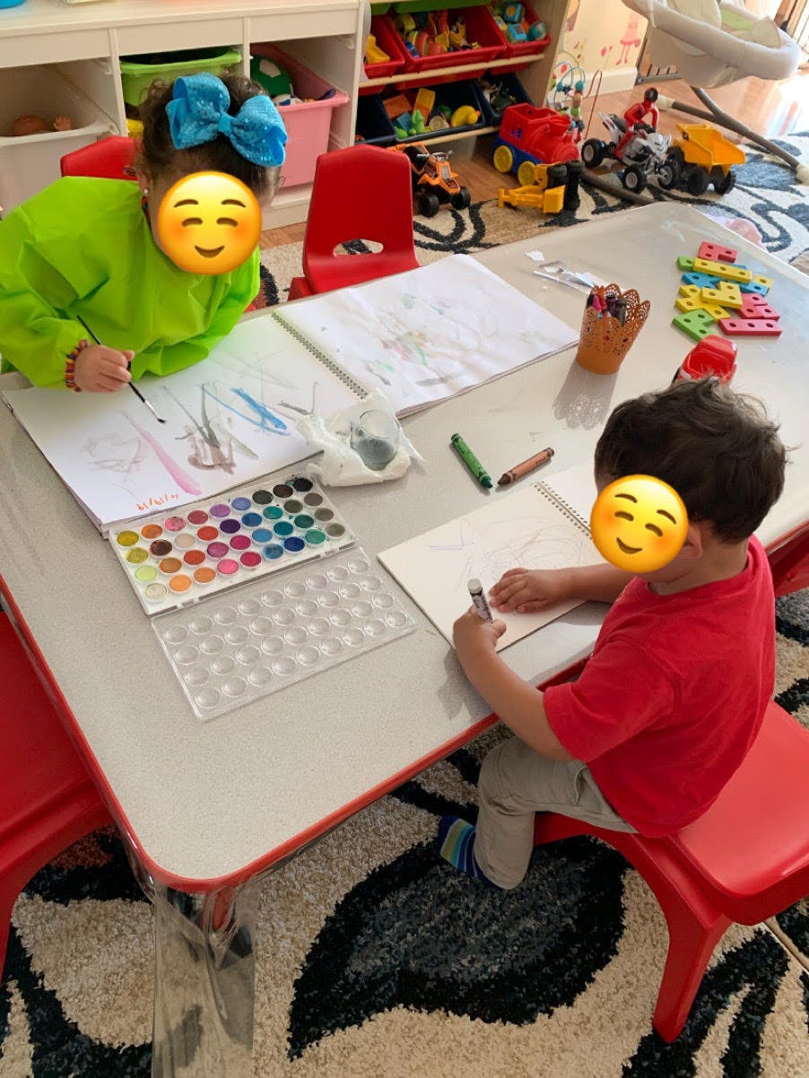 Two children painting and drawing at a table