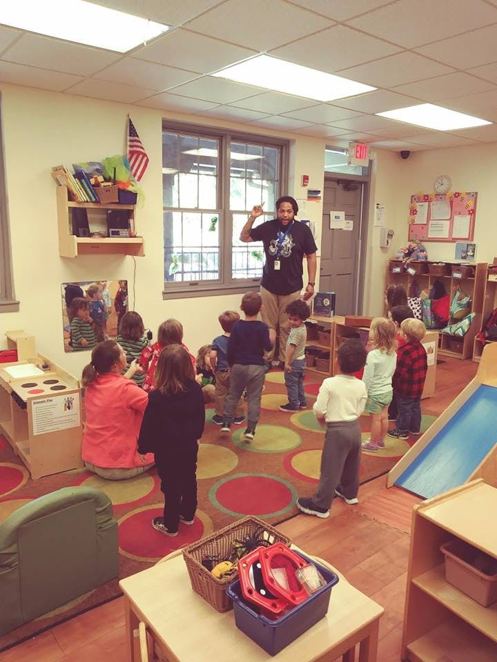 Adult speaking to a group of children in a classroom