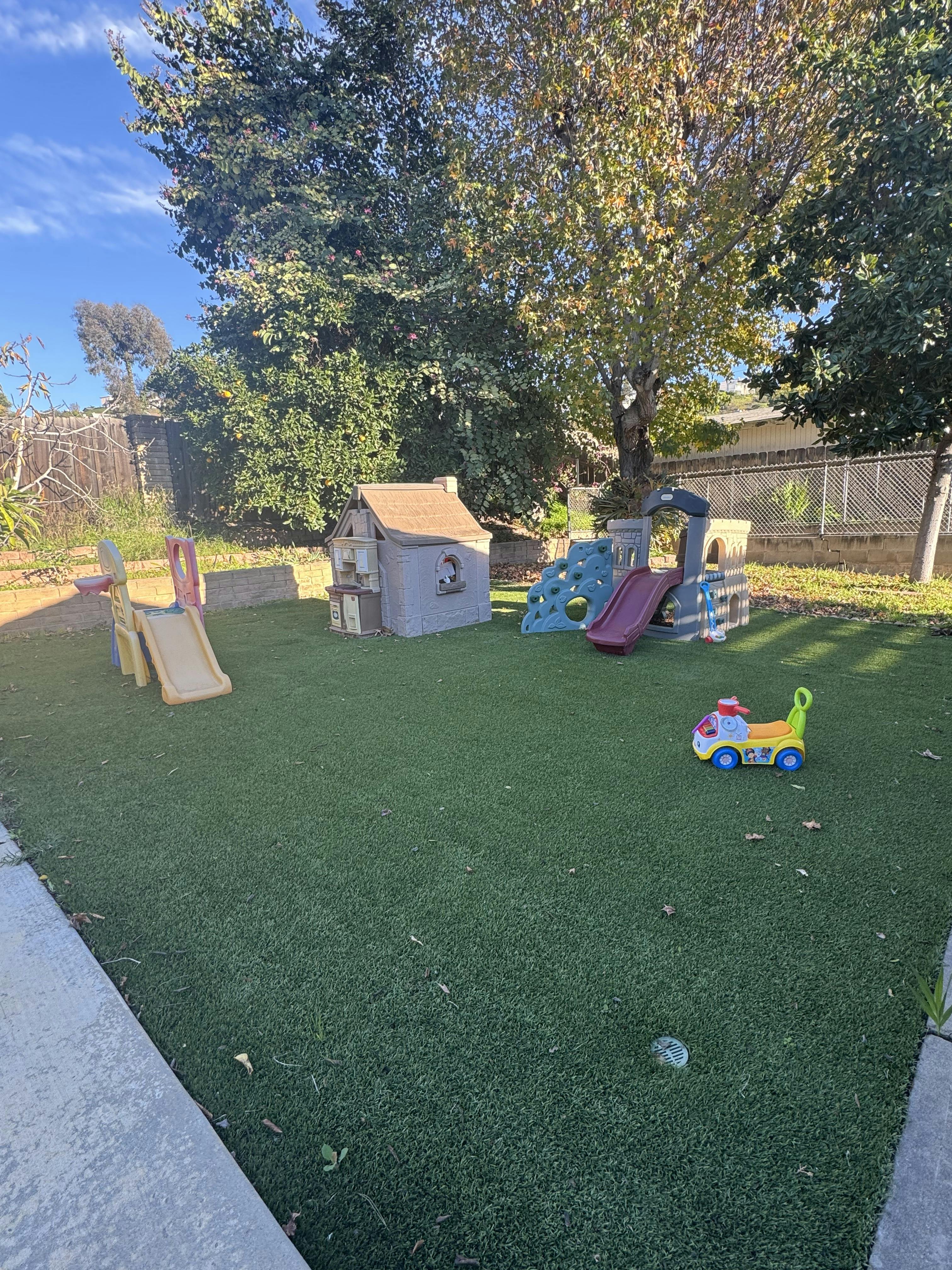 Playground with slides, playhouse, and ride-on toy on artificial turf