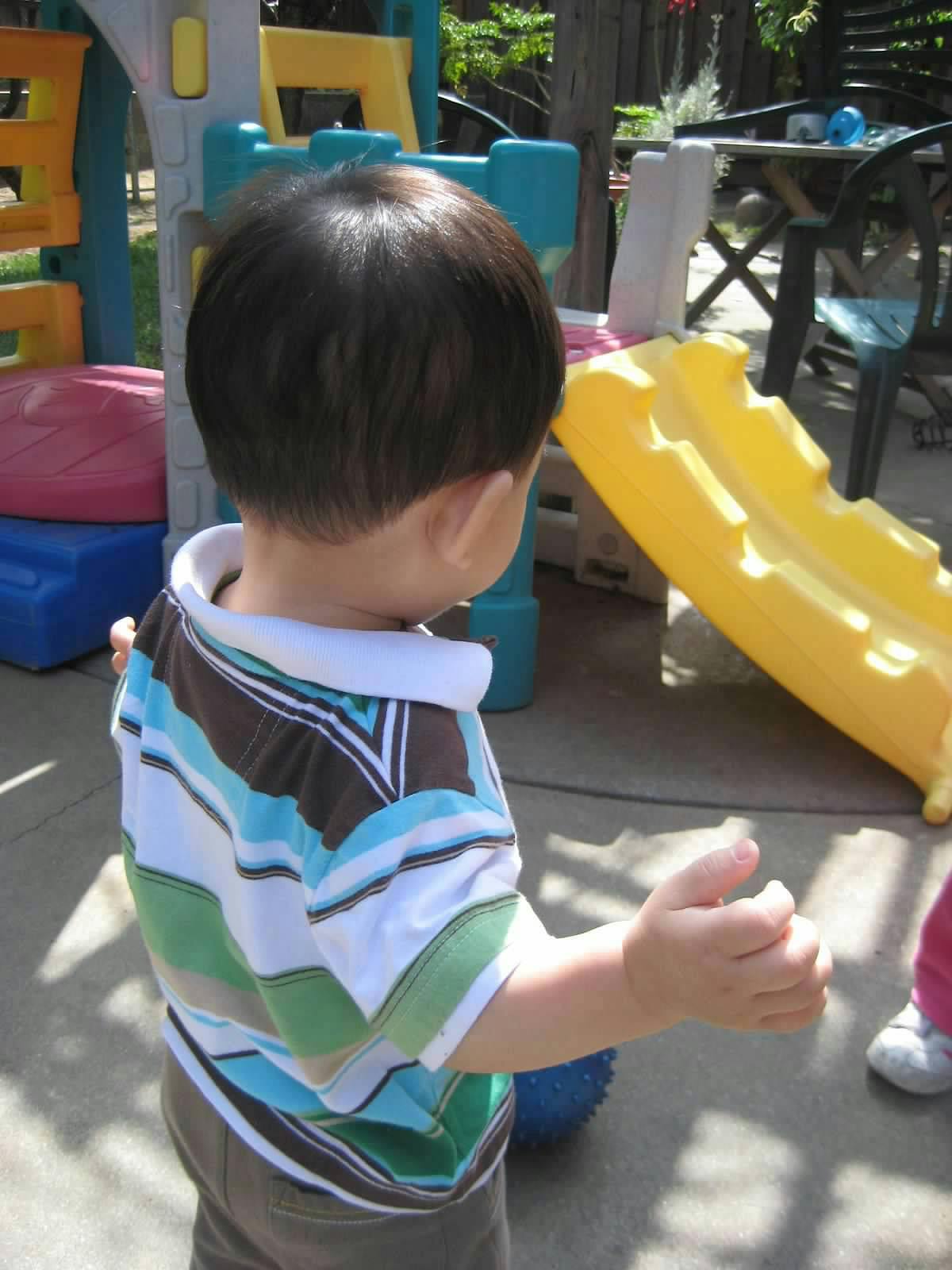 Child in a striped shirt standing near a yellow slide