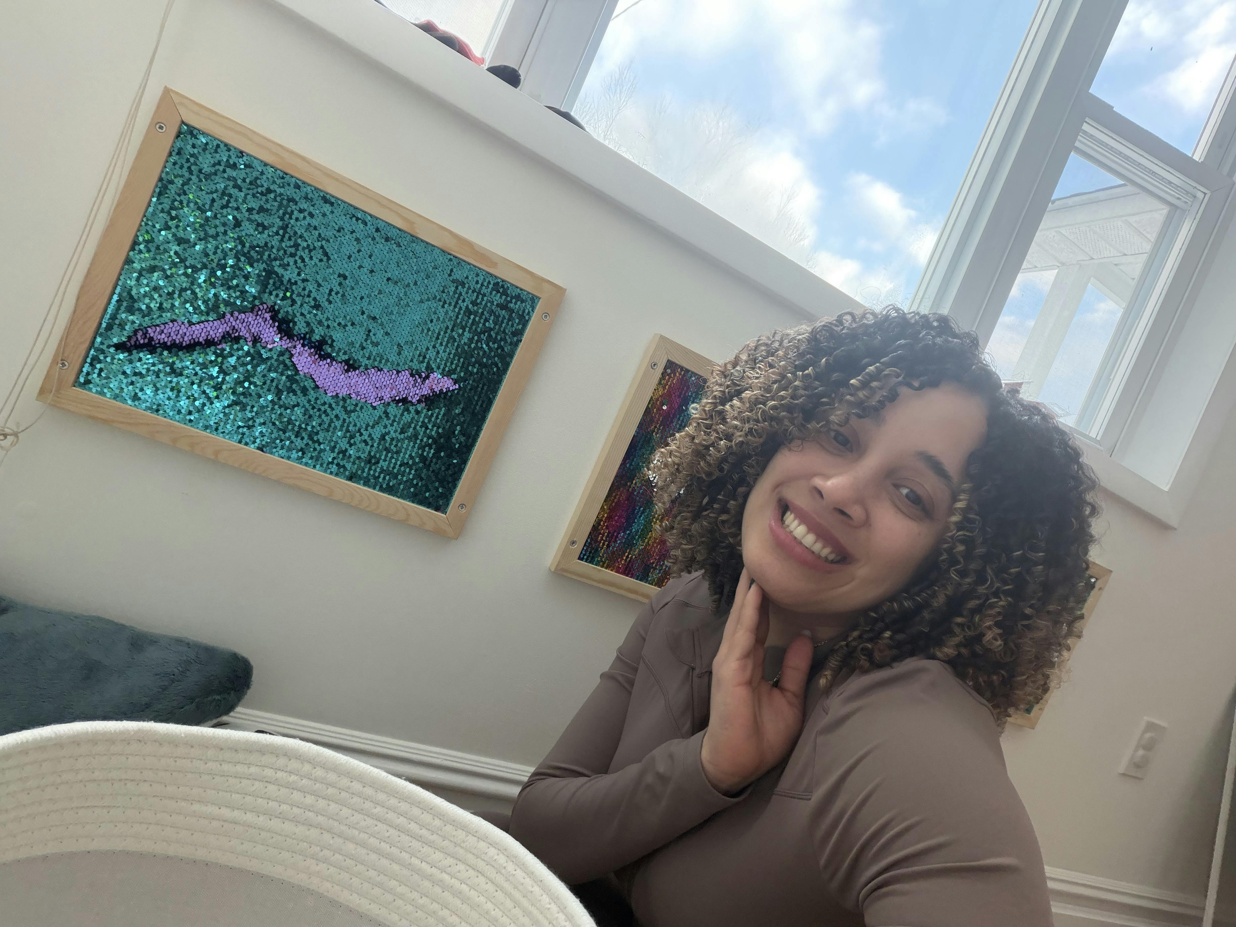 Smiling person with curly hair touching their chin