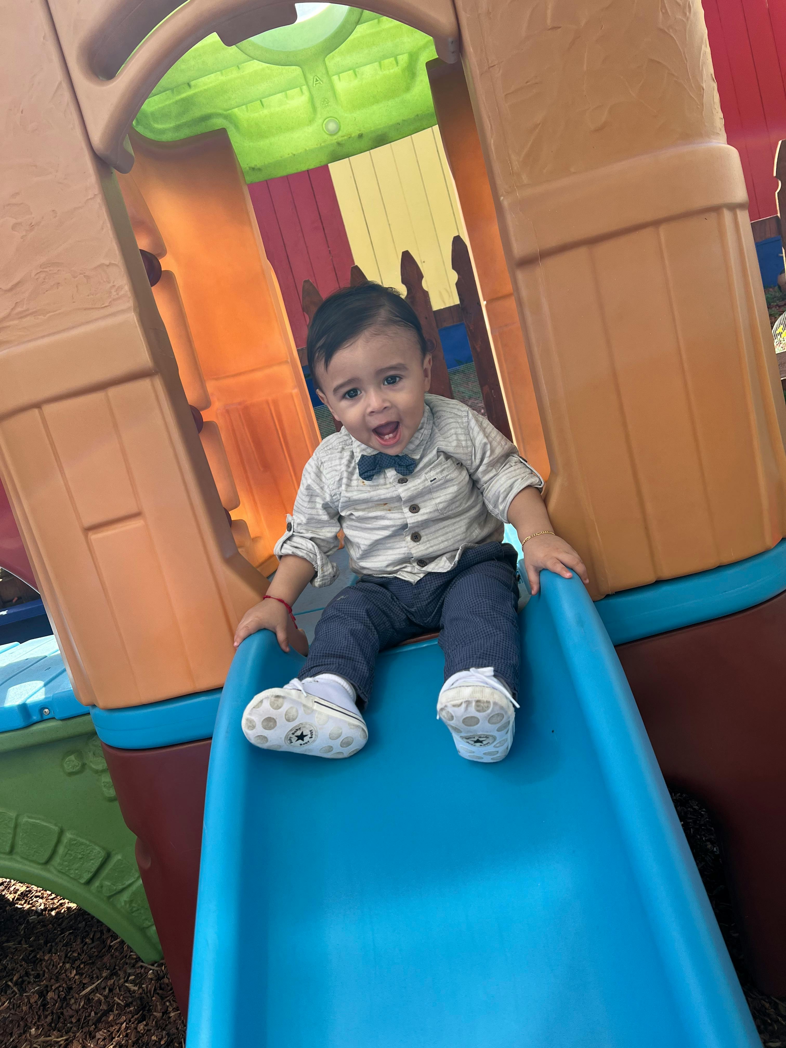 Child sitting on a blue slide on a playground