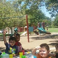 Children at an outdoor table with playground in background