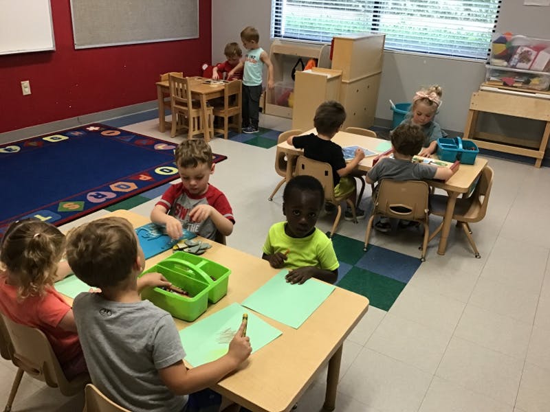 Children sitting at small tables in a classroom