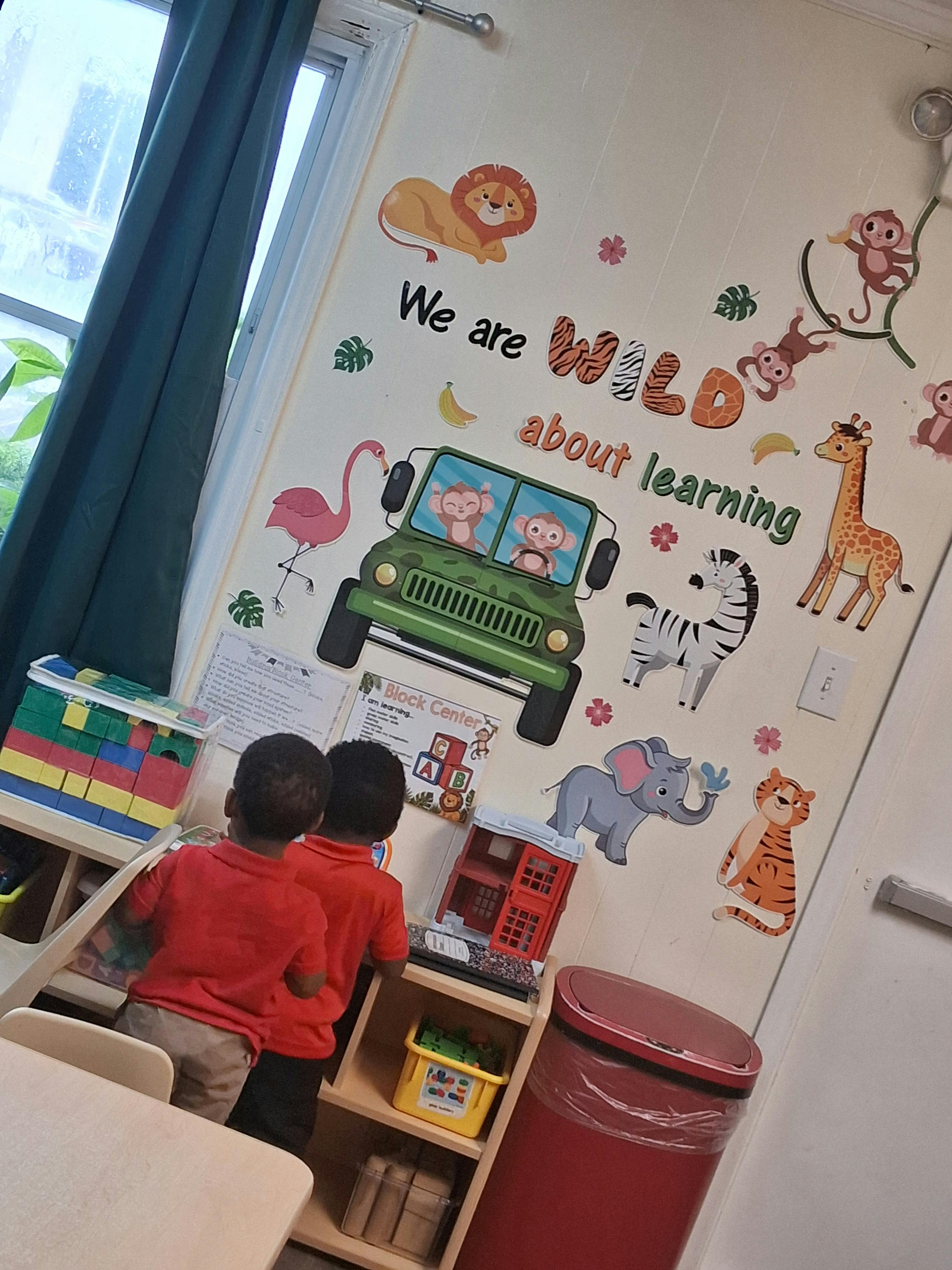Two children playing with building blocks near a decorated classroom wall