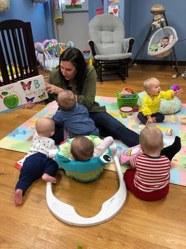 Person reading a book to multiple babies on a playmat