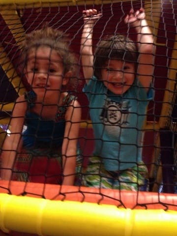 Two children behind a net in an indoor play area