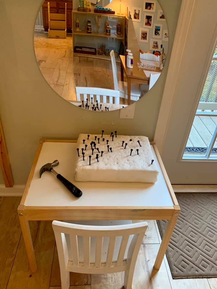 Hammer and nails in a block of foam on a small table