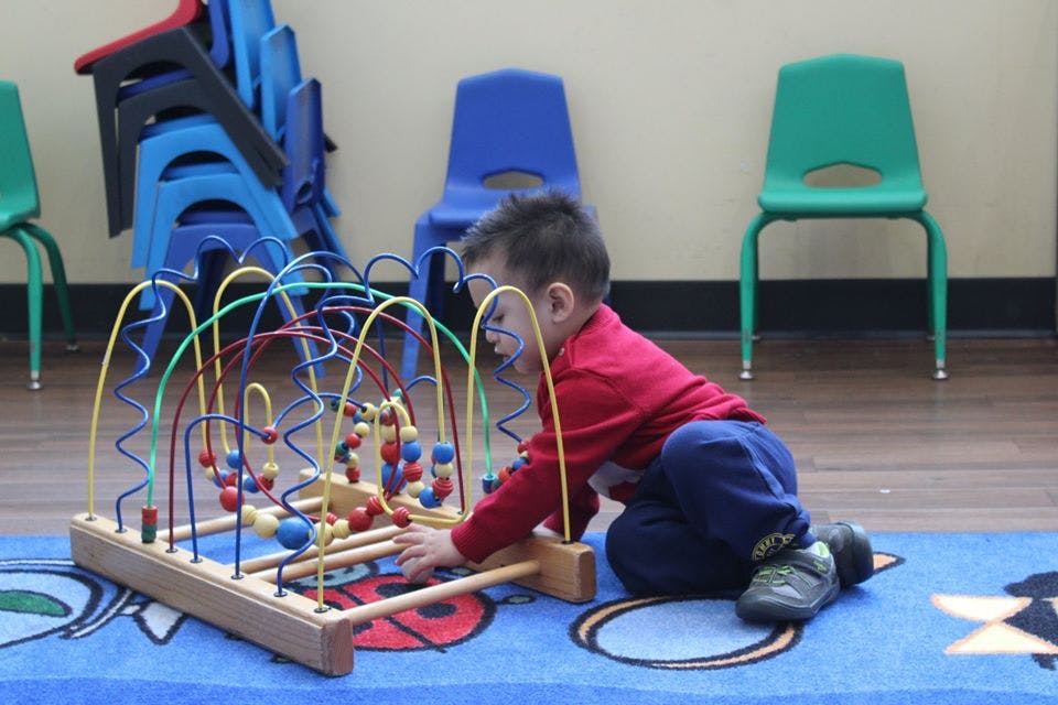Child playing with a bead maze toy on a rug