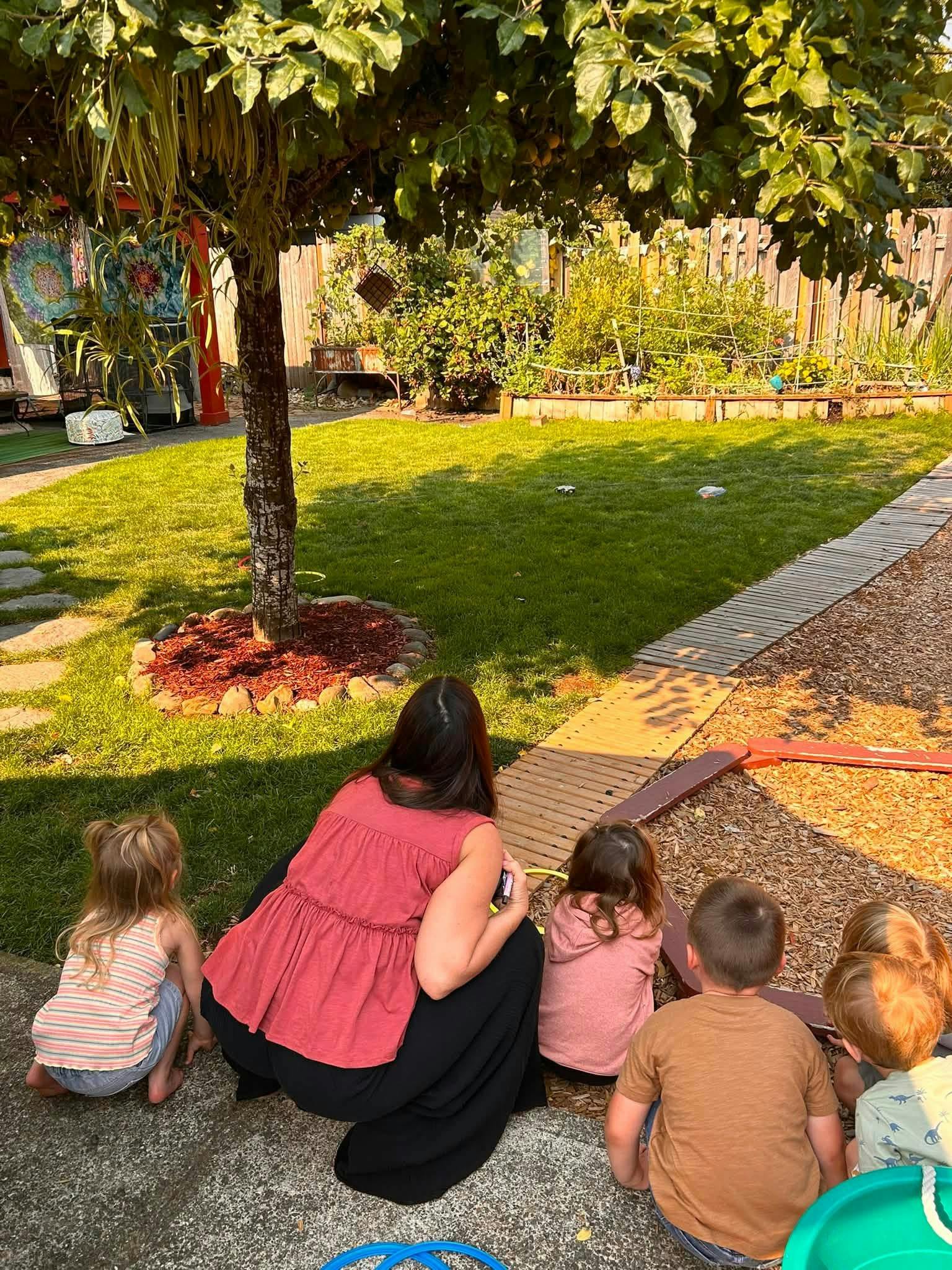 A group of children and an adult looking toward a grassy yard