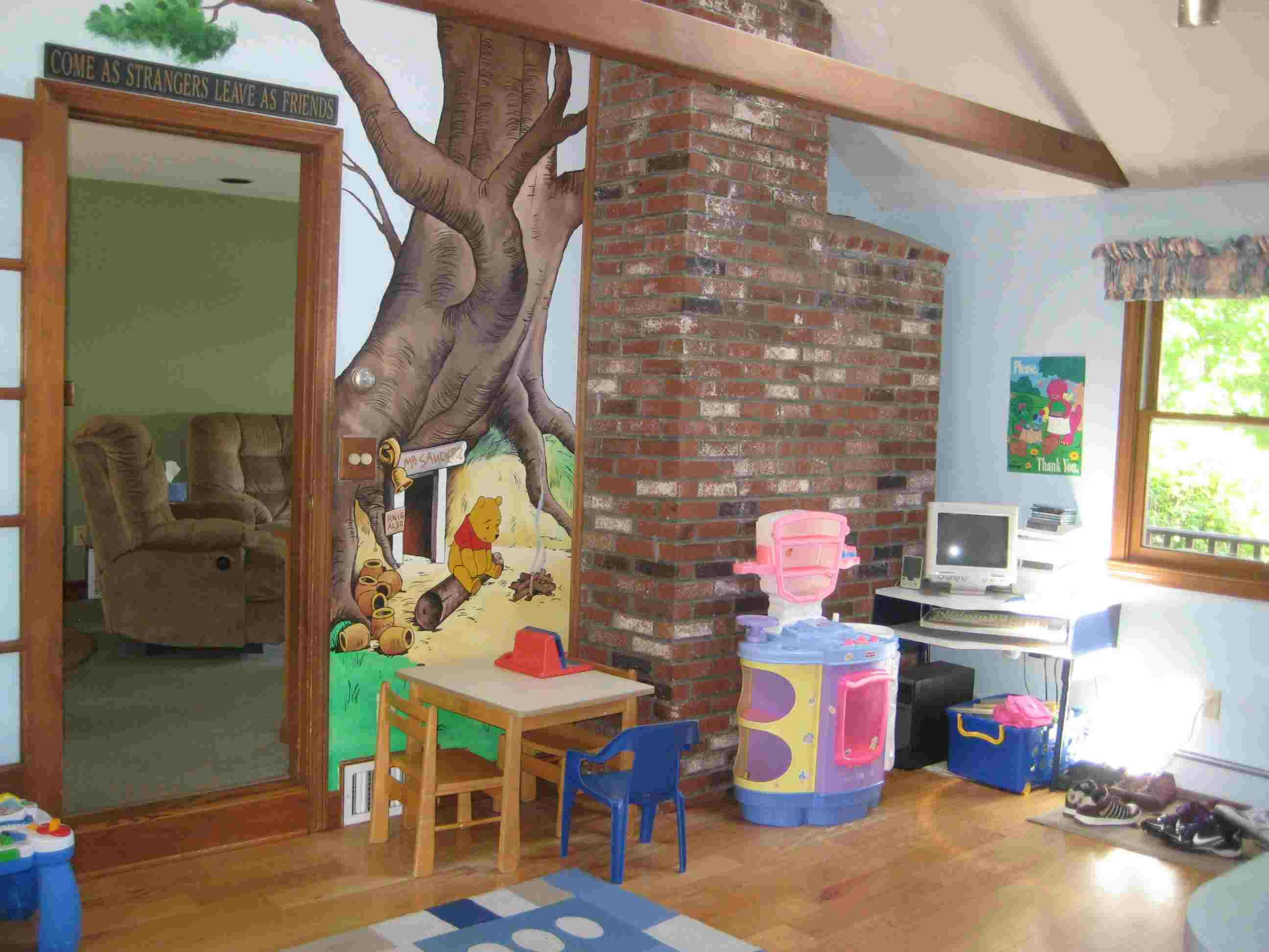 Playroom with a tree mural, small table and chairs, and a computer desk