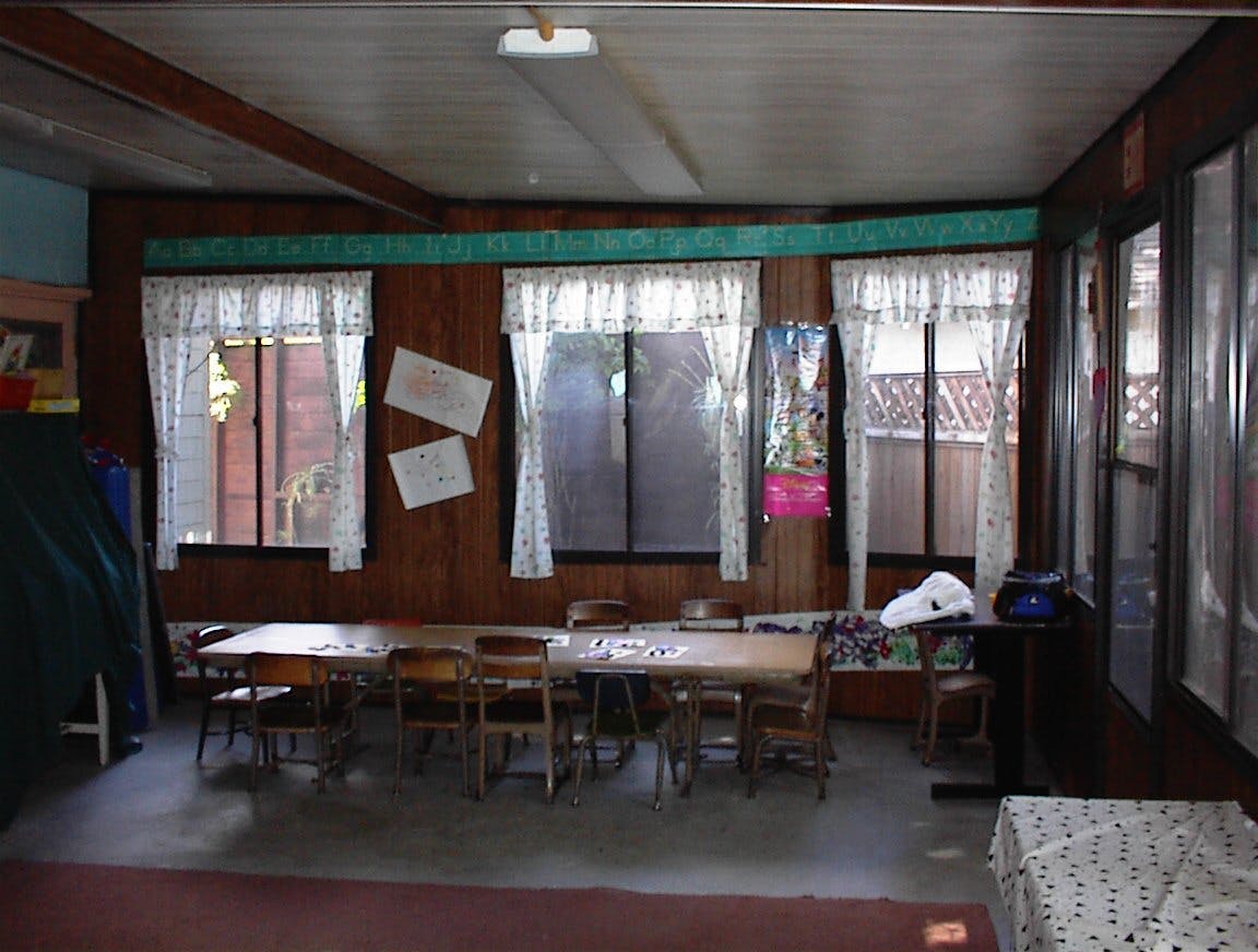 Classroom with tables and chairs, windows with curtains