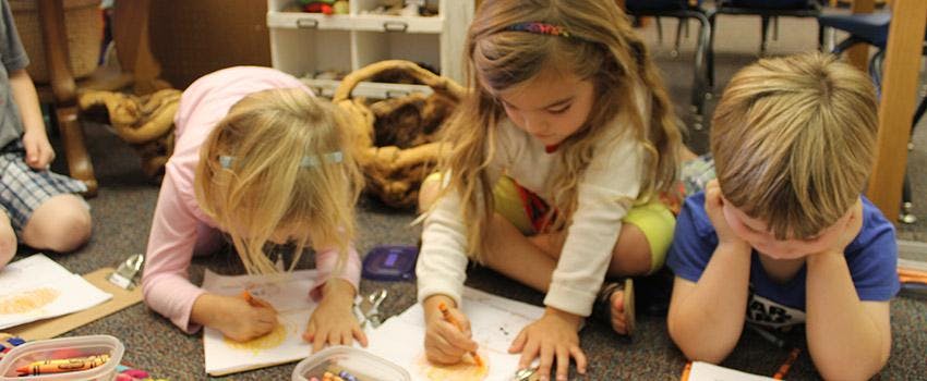 Three children drawing on the floor