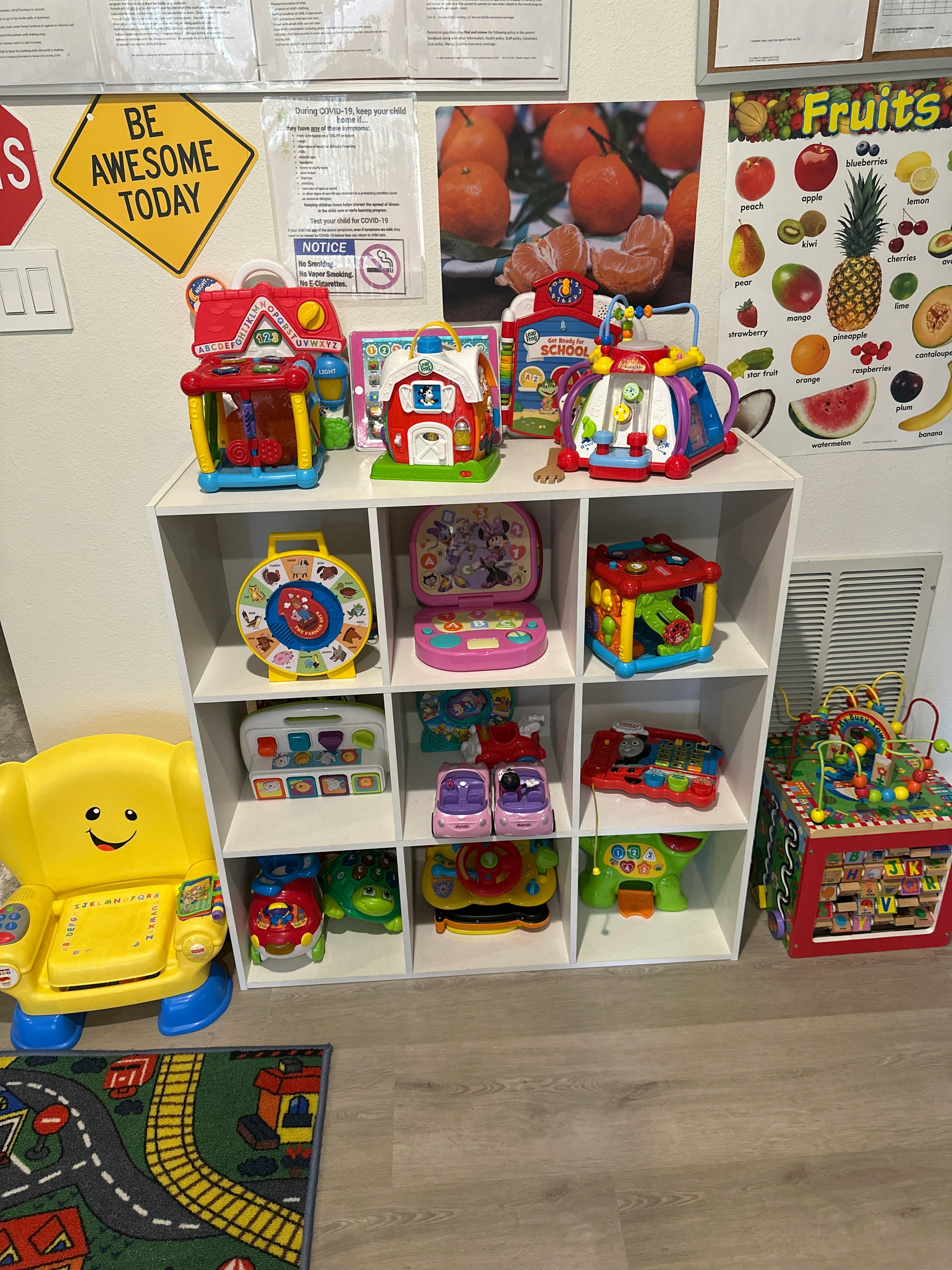 Wall with a colorful fruit chart, a 'BE AWESOME TODAY' sign, and children's toys