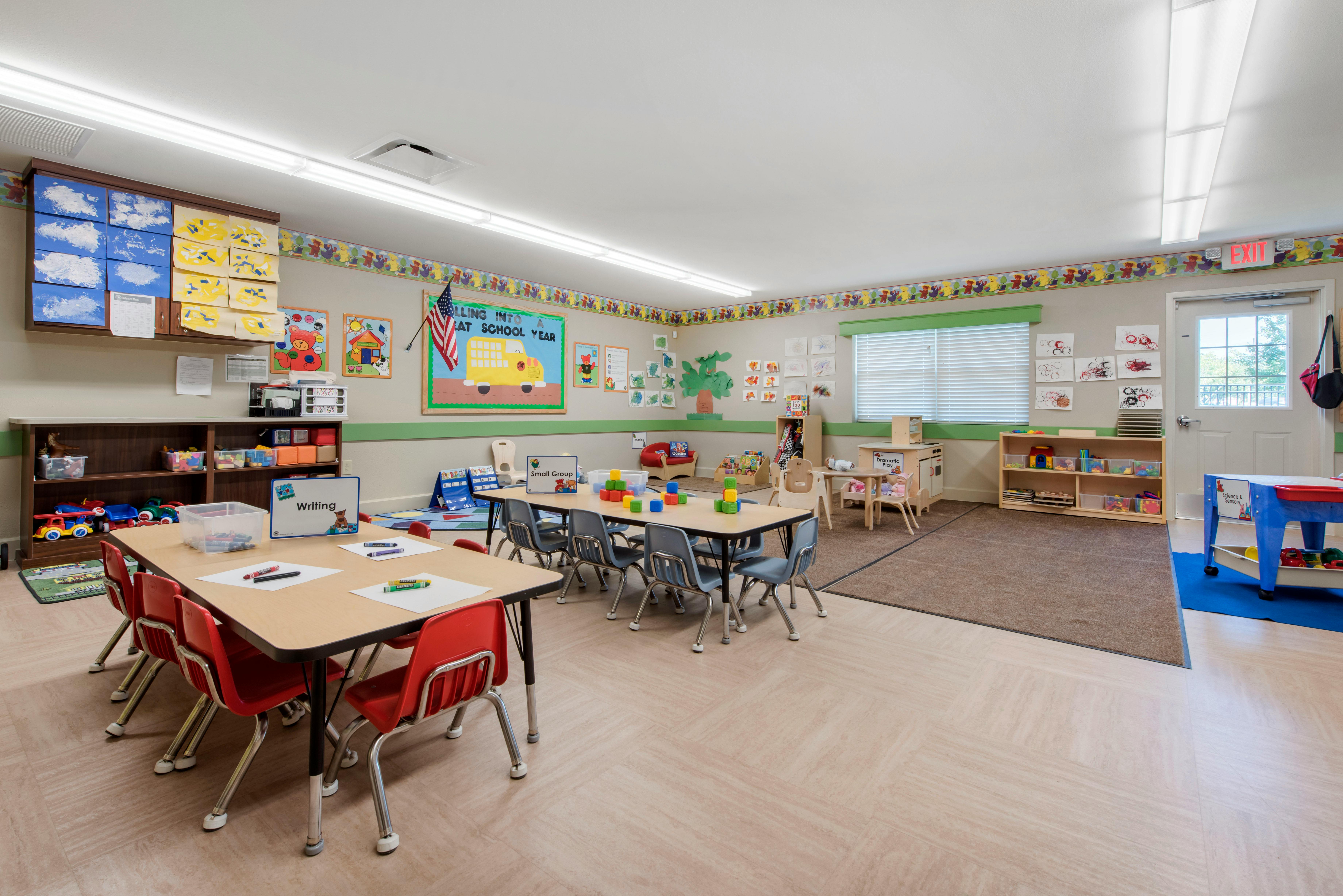 Classroom with child-sized tables and chairs, toys, and colorful artwork on the walls