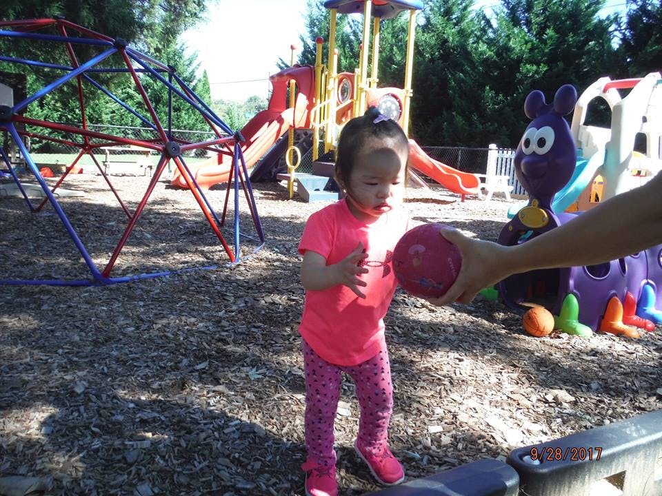Child reaching for a ball on a playground