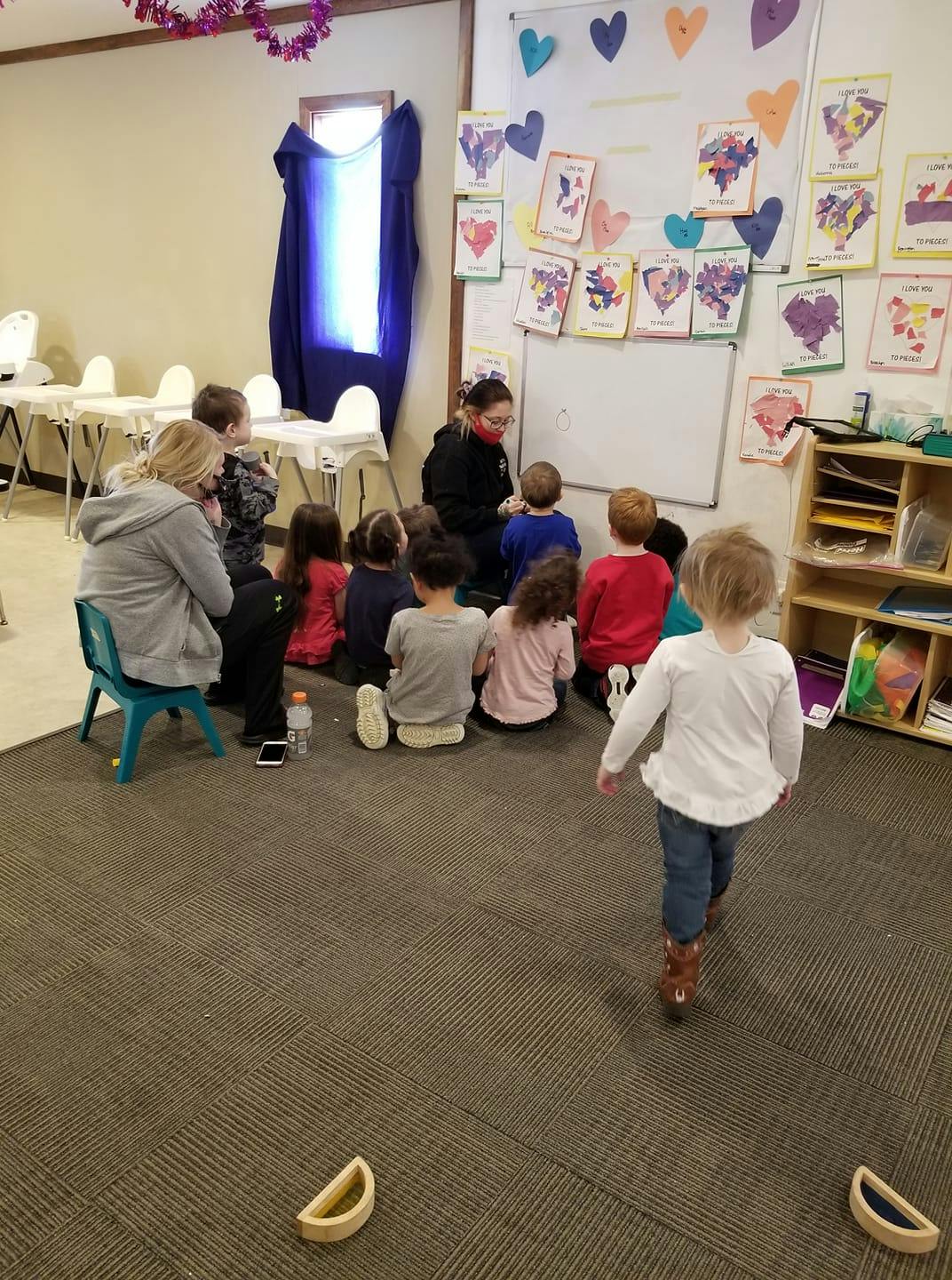 Adults and children sitting on the floor in a classroom