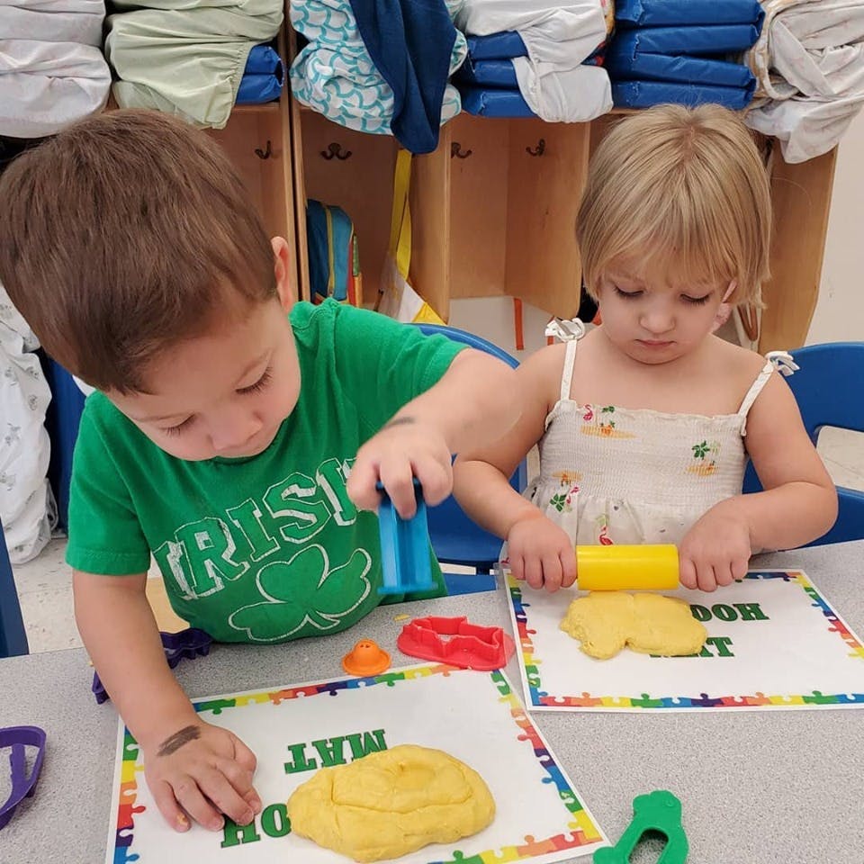 Two children playing with play-doh and tools at a table