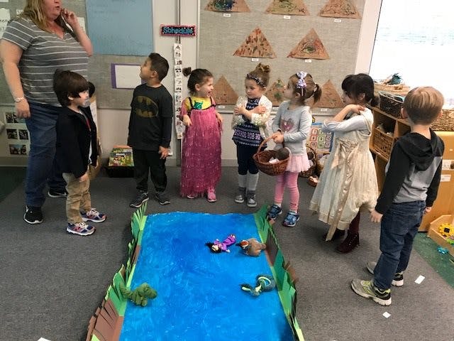 Adult and children gathered around a blue play mat with toys