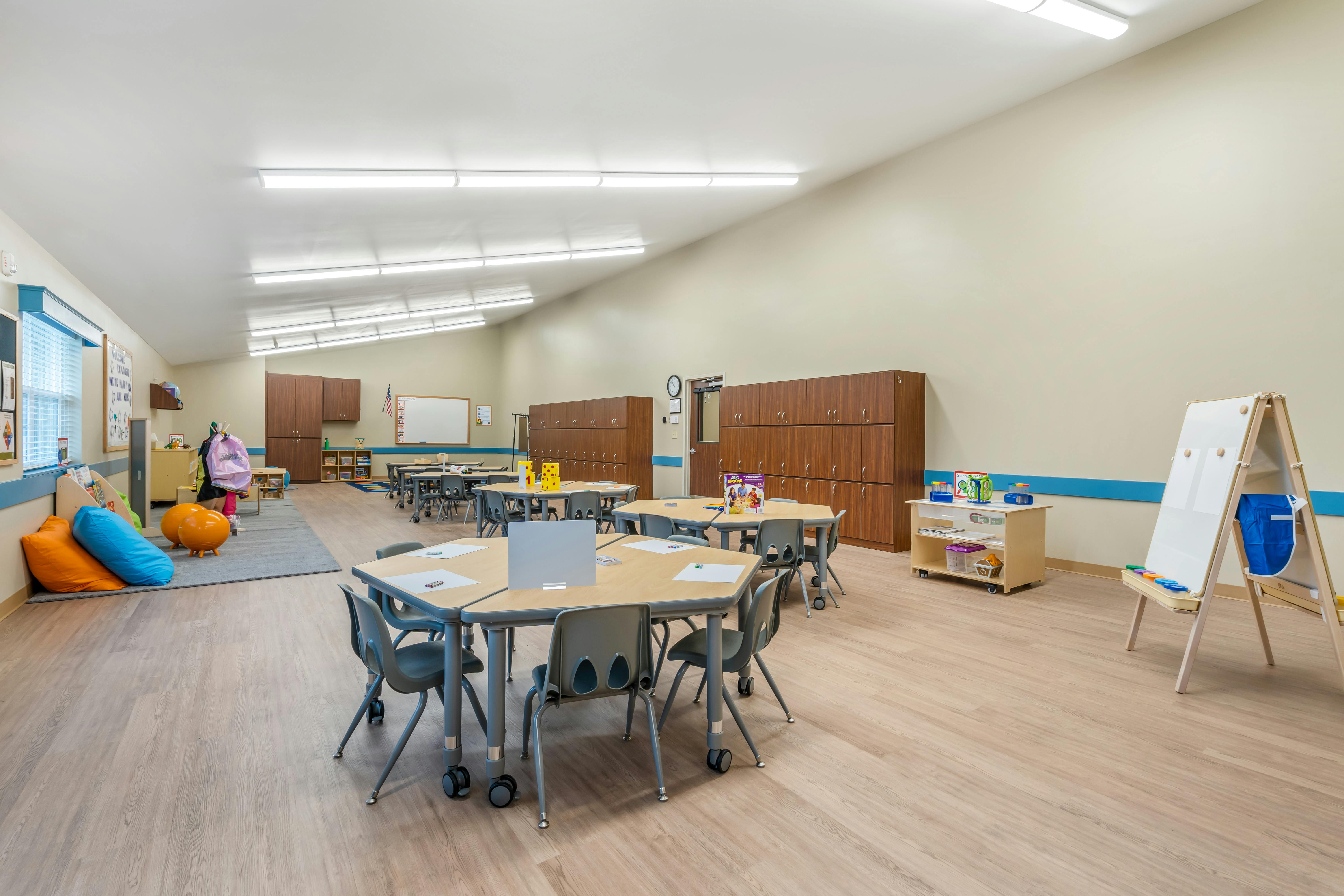 Classroom with tables and chairs, beanbags, and storage cabinets