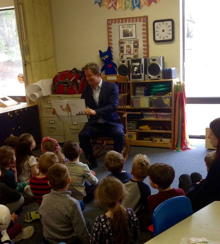 Person reading a book to a group of children in a classroom