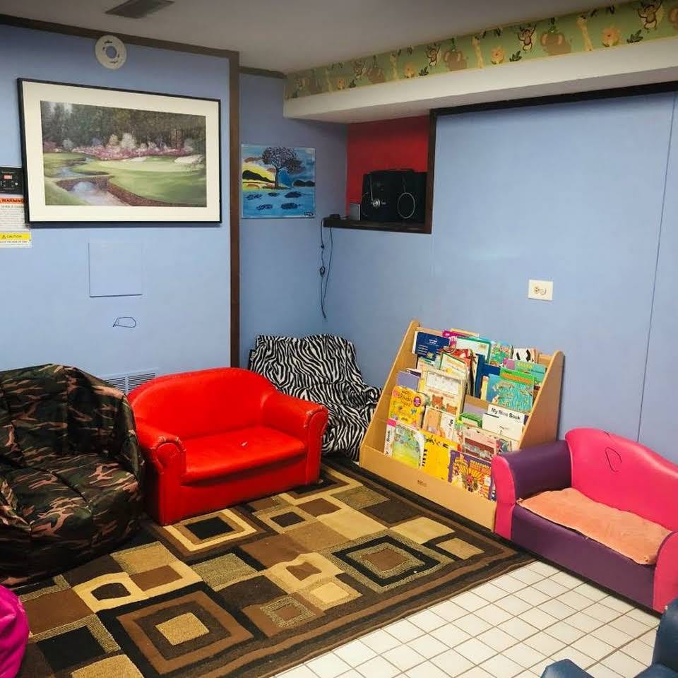 Children's seating area with a bookshelf, rug, and various chairs