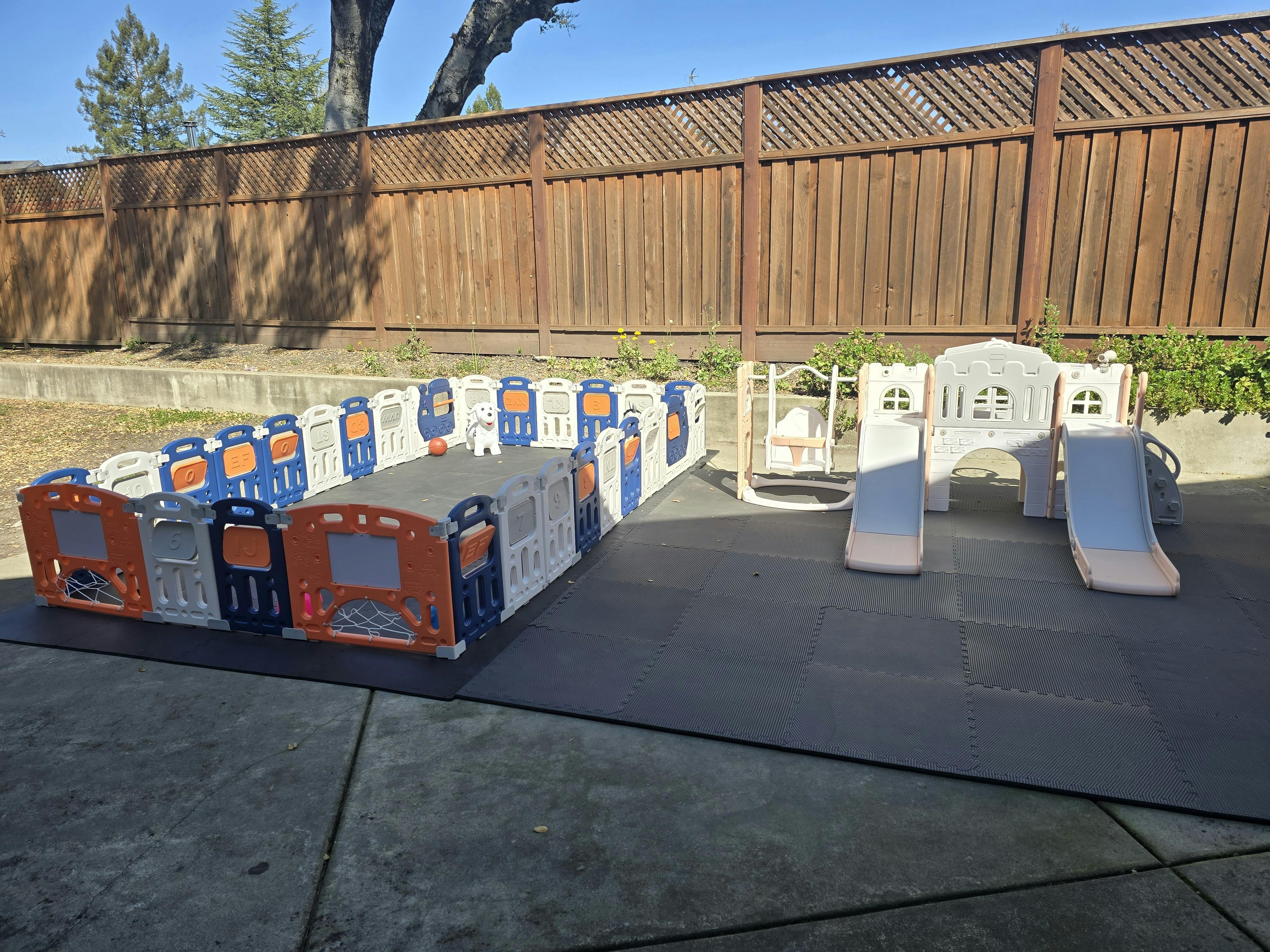 Play area for children with a modular fence, swing, and double slides