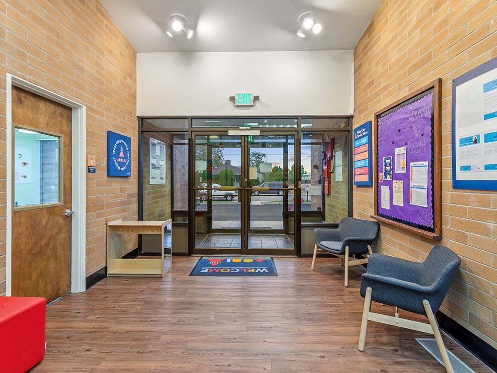 Lobby with brick walls, glass door exit, chairs, and bulletin boards