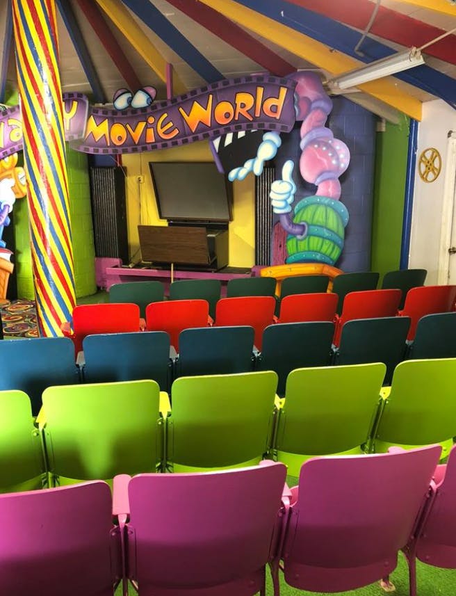 Rows of colorful chairs facing a screen under a "Movie World" sign