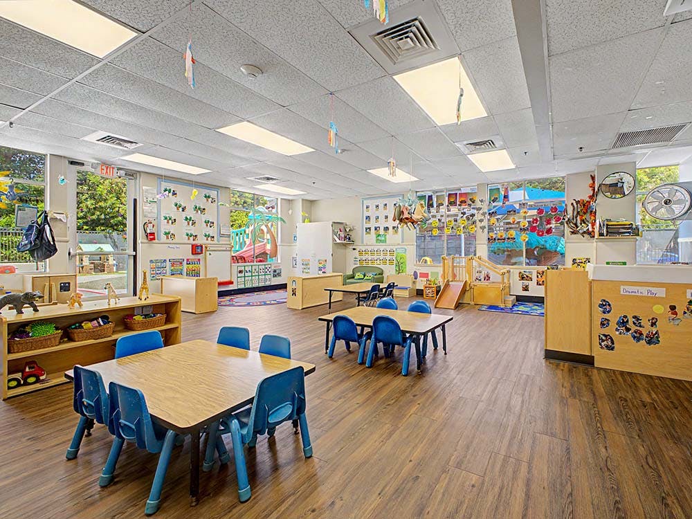 Empty colorful preschool classroom with small tables and chairs