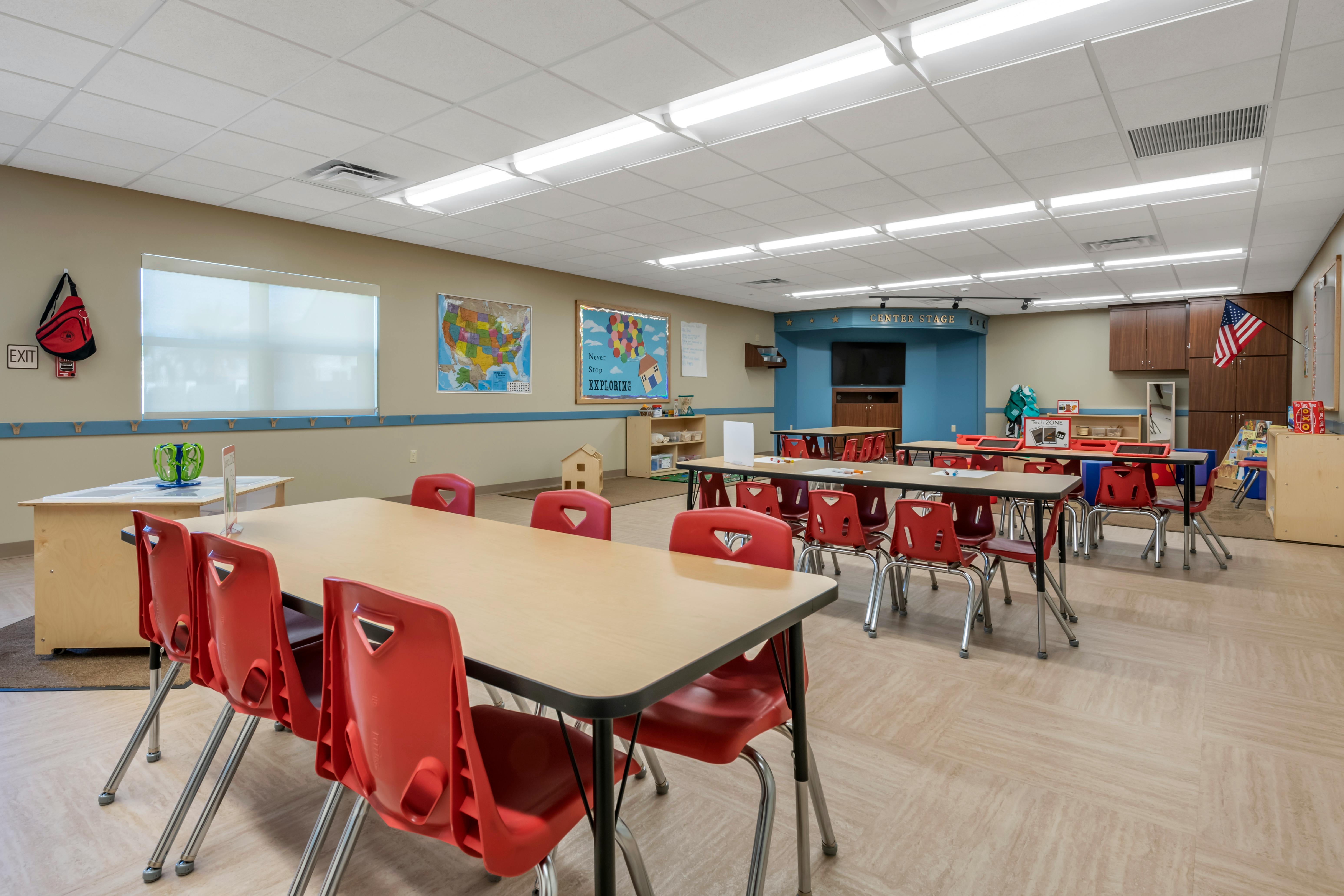 Classroom with tables and chairs, a map, and a bulletin board that says Never Stop Exploring