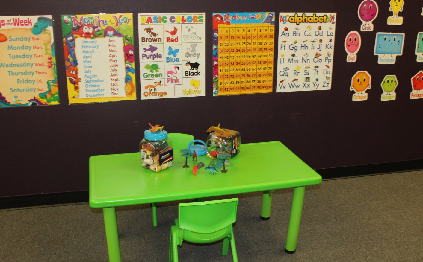 Green table and chair in a classroom with educational posters on the wall