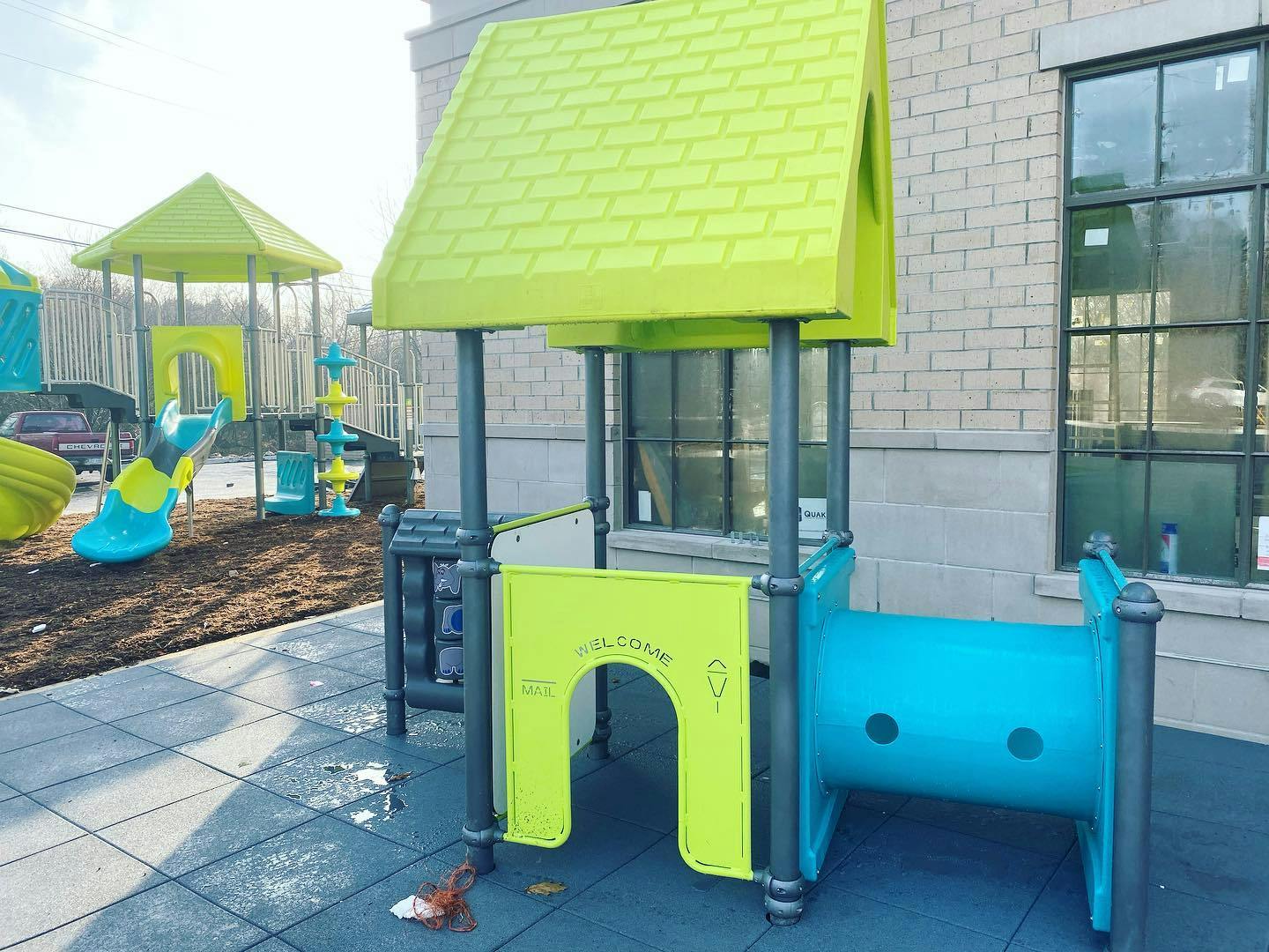 Playground structure with a green roof and blue tunnel