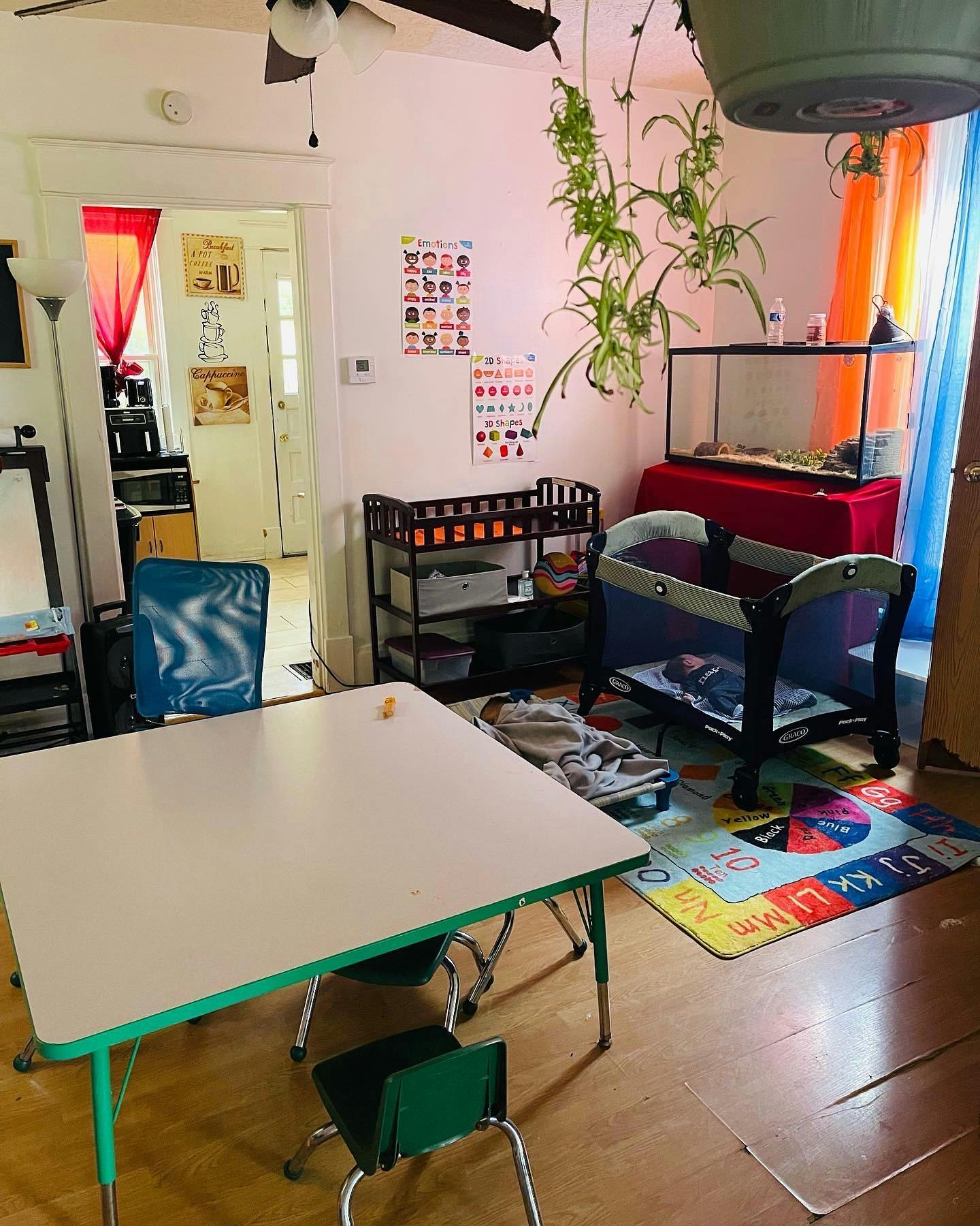 Child's table and chairs, playpen, and changing table in a room