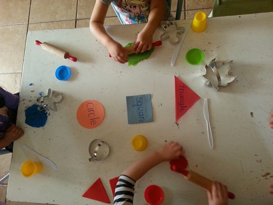 Children playing with playdough and cookie cutters on a table