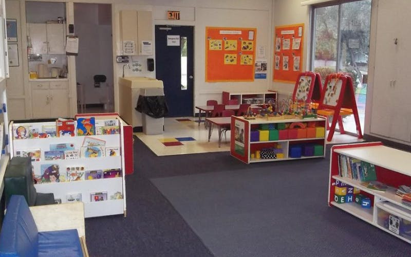 Classroom with child-sized tables, easels, and shelves filled with books and toys