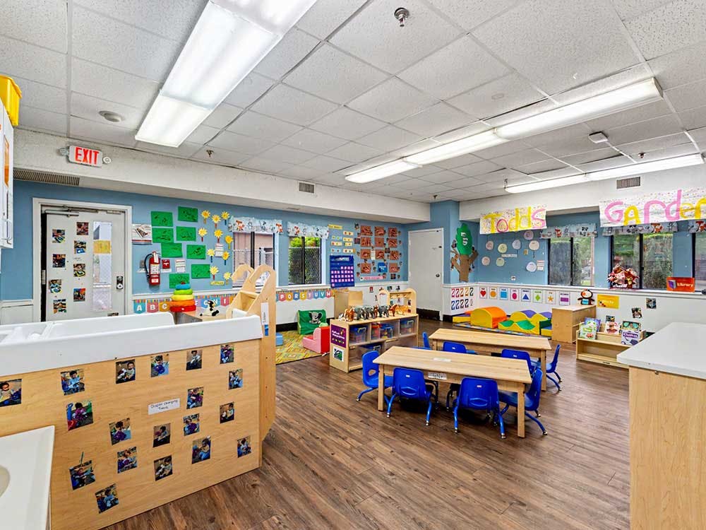 Children's classroom with small tables and chairs, and a changing station