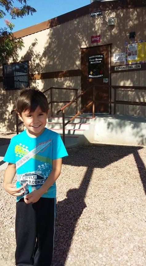 Child in a blue shirt standing outside a building