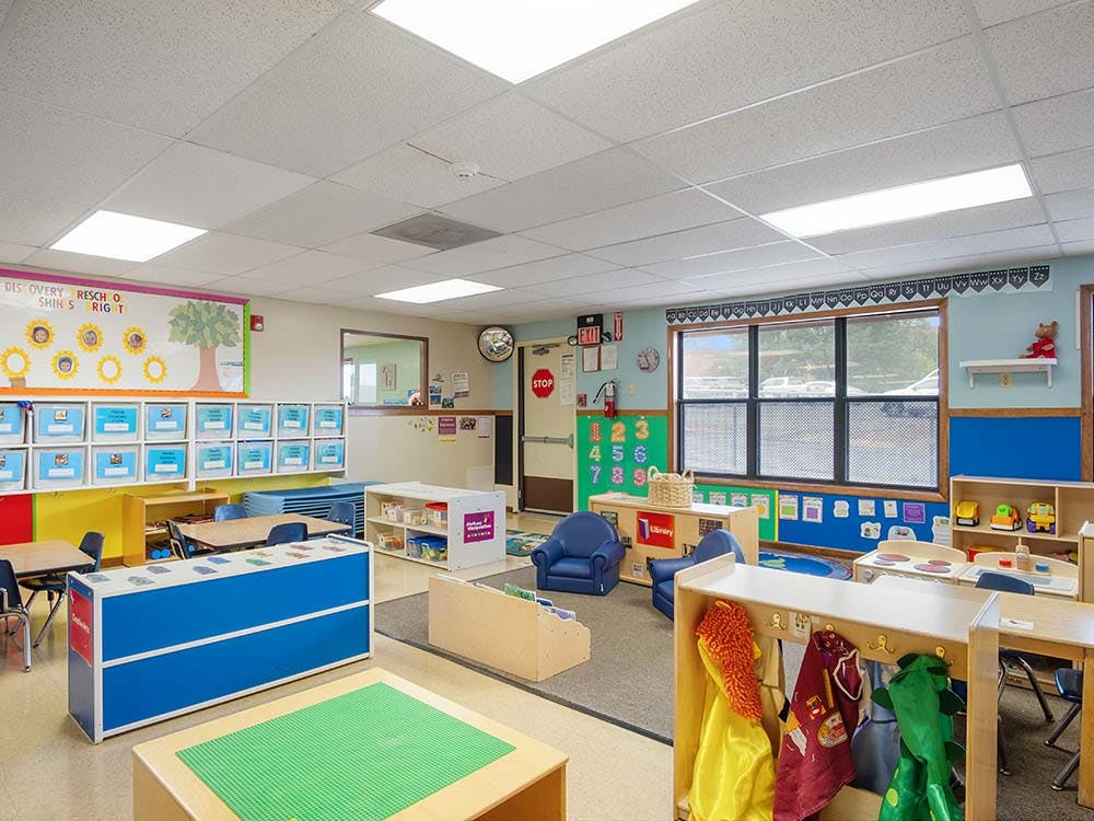 An empty preschool classroom with colorful furniture and storage