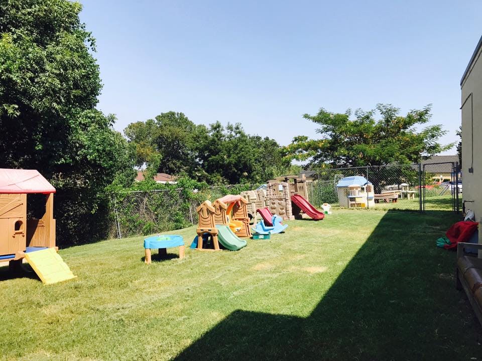 Outdoor playground with various slides and playhouses on a grassy area