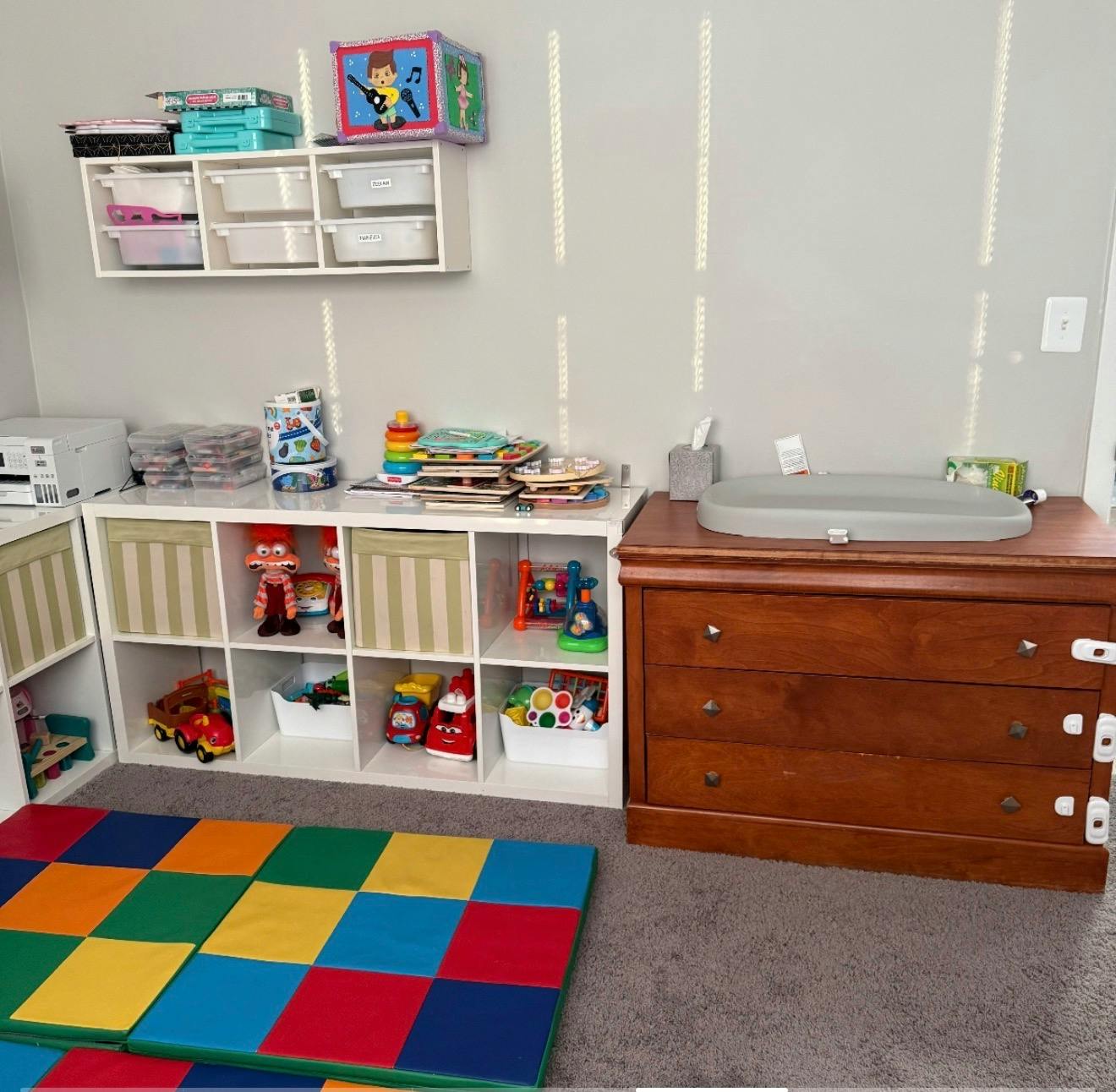 Children's room with toys, storage cubes, and a changing table on a dresser