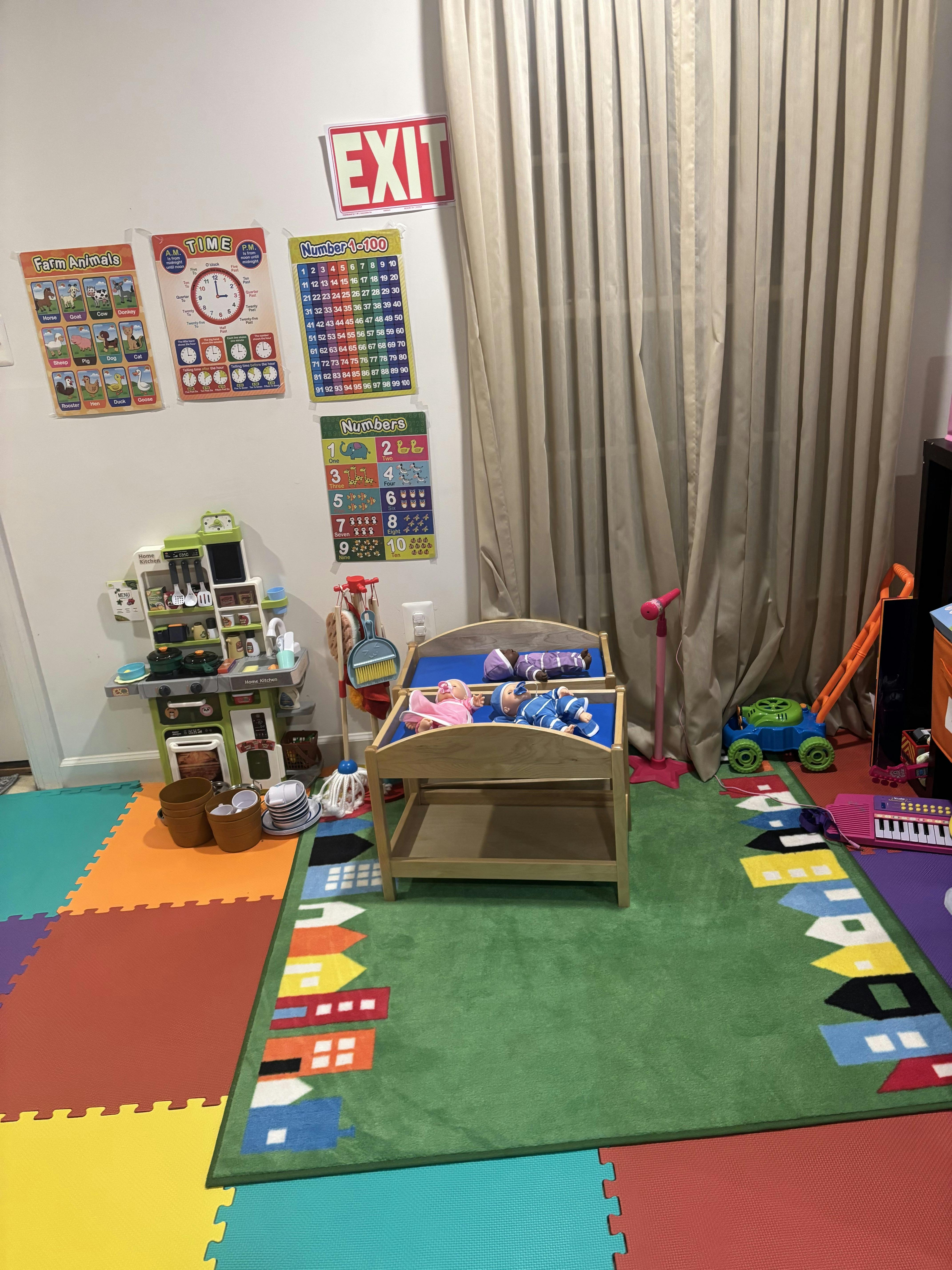 Play area with toy kitchen, doll bed, and educational wall posters