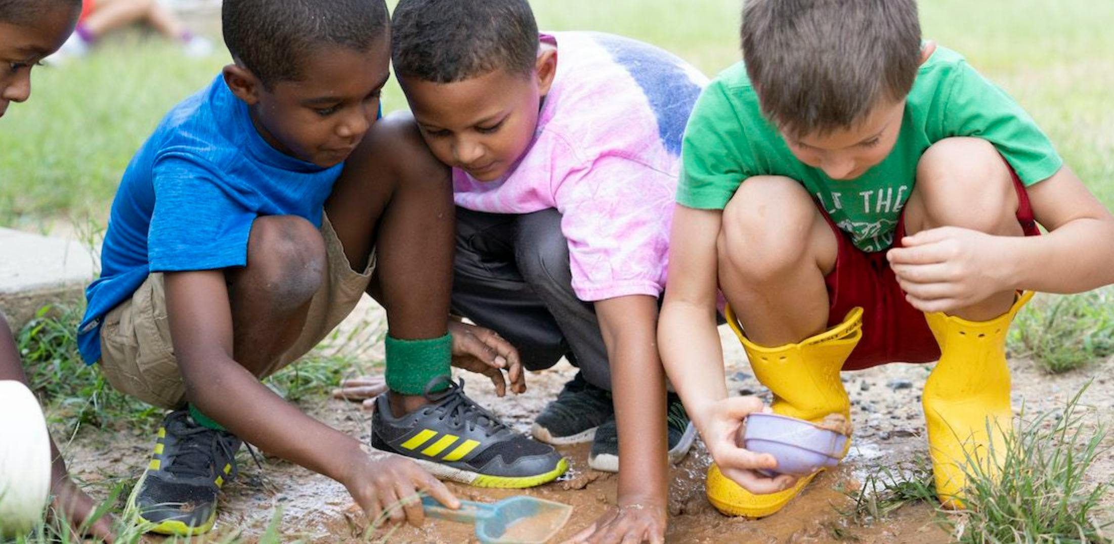 Children playing in mud with a small shovel