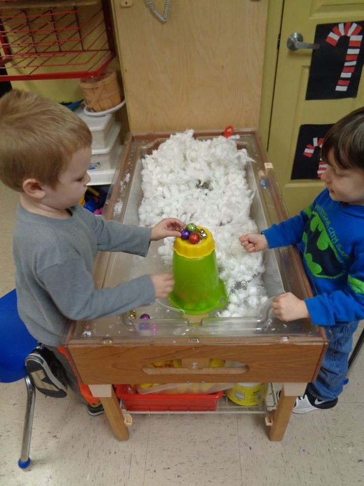 Two children playing at a sensory table filled with white material