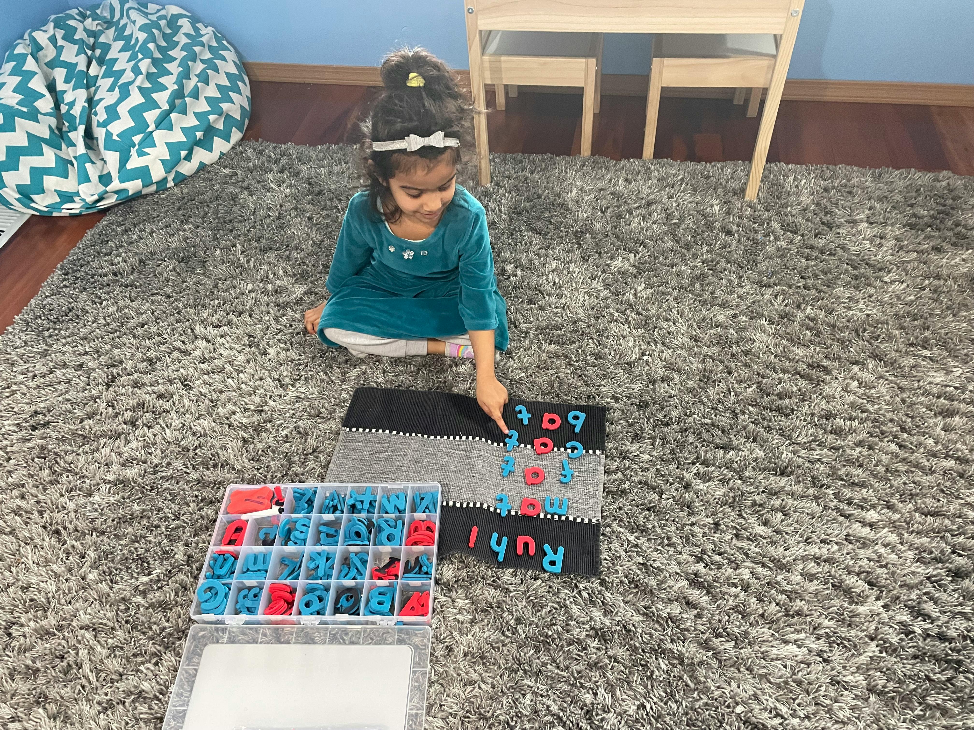 Child on floor playing with letter tiles
