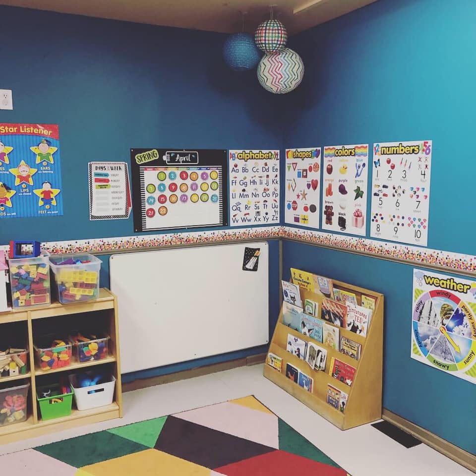 Classroom with educational posters, storage shelves, and a book display