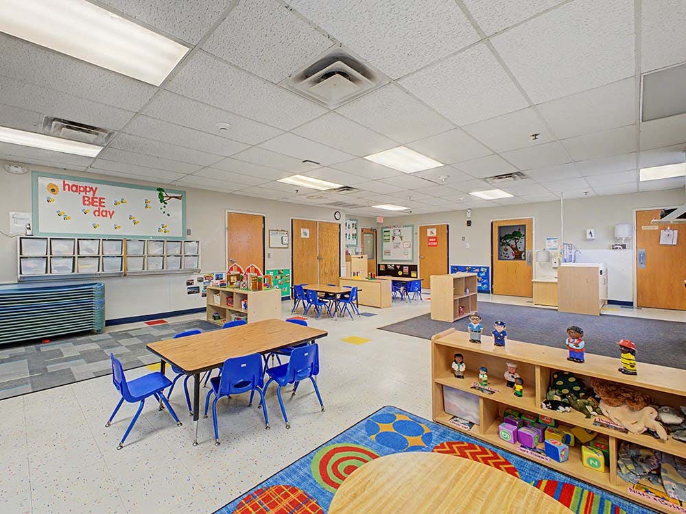 Empty classroom with small tables and chairs, storage, and a whiteboard